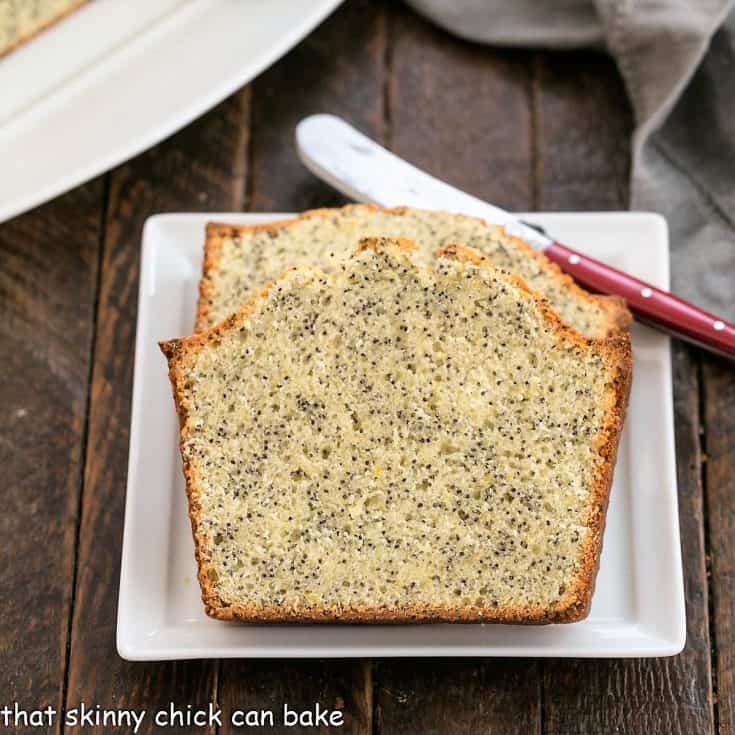 2 slices of lemon poppy seed bread on a square white plate with a red handle knife