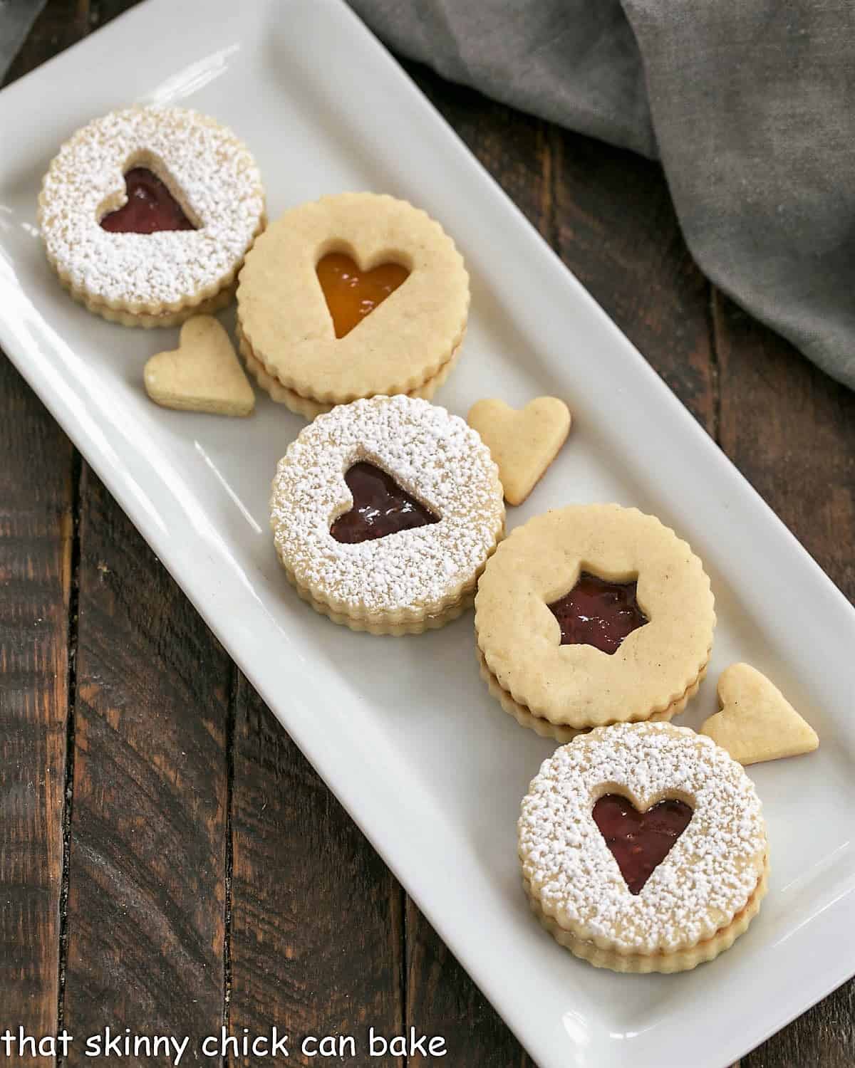 Overhead view of linzer cookies on a white ceramic tray.
