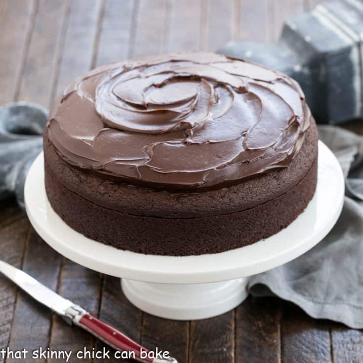 Frosted Mud Cake on a white cake stand with a red handle knife