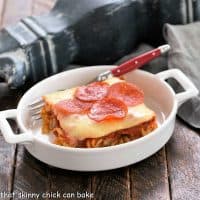 slice of pizza casserole in a small white casserole dish