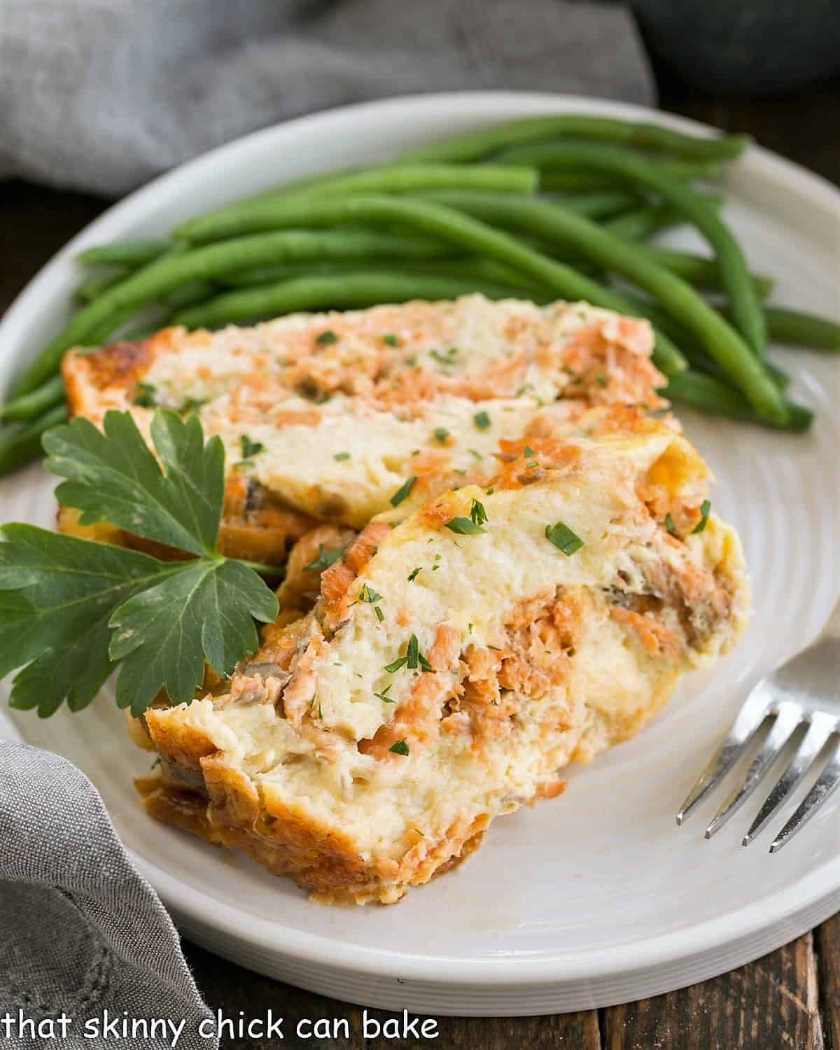 2 slices of salmon loaf on a round white plate with green beans.
