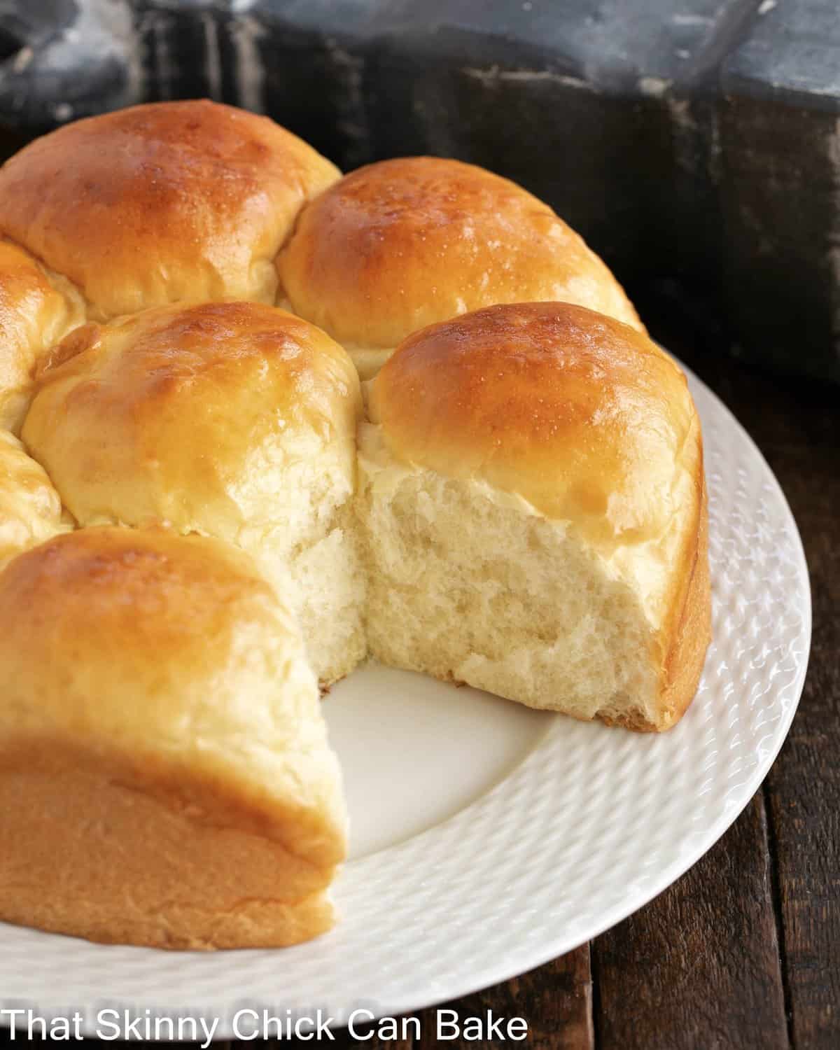 Japanese milk buns on a white serving plate with one removed.