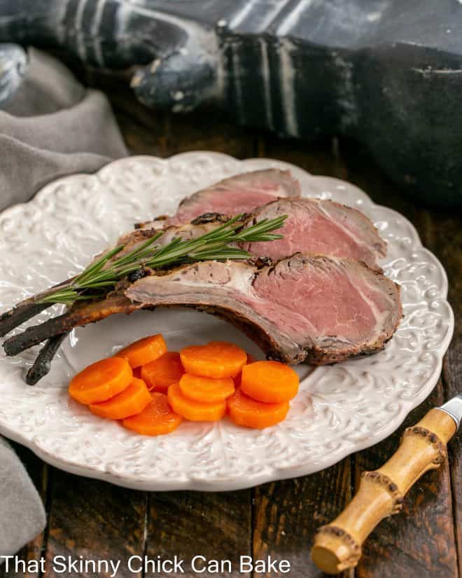 overhead view of frenched lamb chops on a white plate with a bamboo handled fork