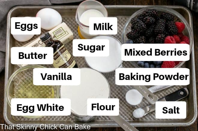 Labeled berry cake ingredients on a metal sheet pan.