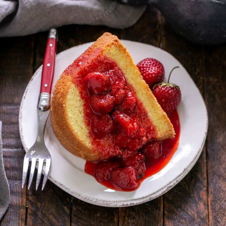 Strawberry compote over a slice of pound cake on a white dessert plate