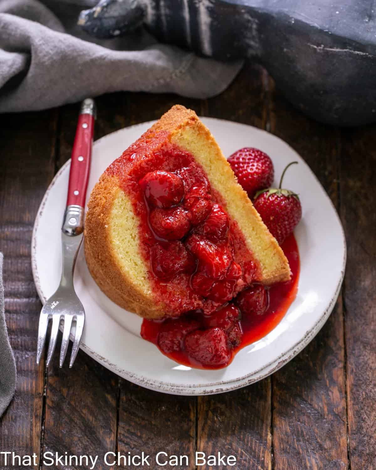 Overhead view of a slice of lemon bundt cake topped with strawberry coulis on a white dessert plate.