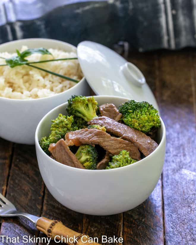Beef stir fry recipe in a white bowl in front of a bowl of rice