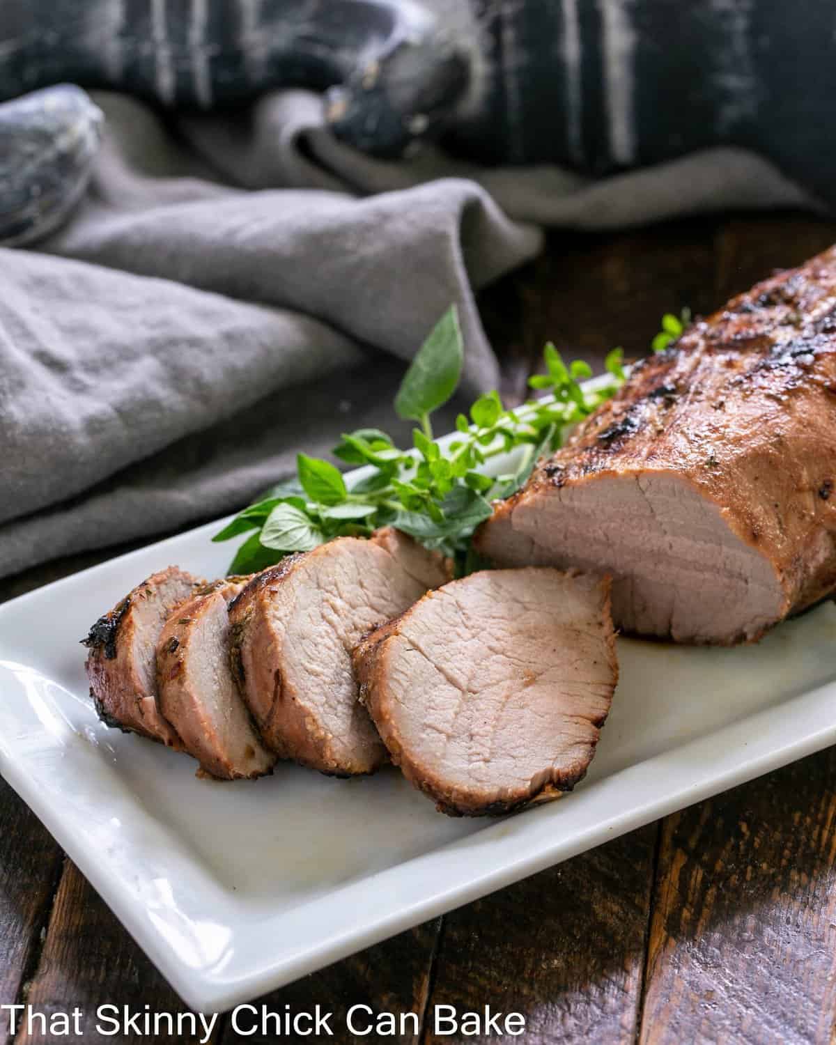 Sliced pork tenderloin on a white tray grilled with an easy pork marinade.