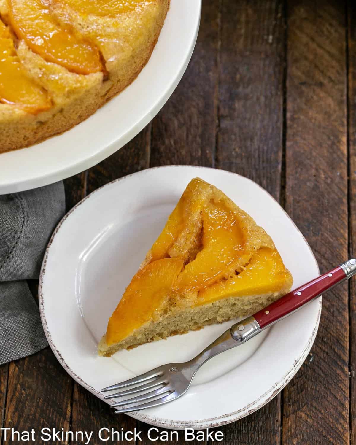 A slice of upside down cake with peaches on a white plate viewed from above.