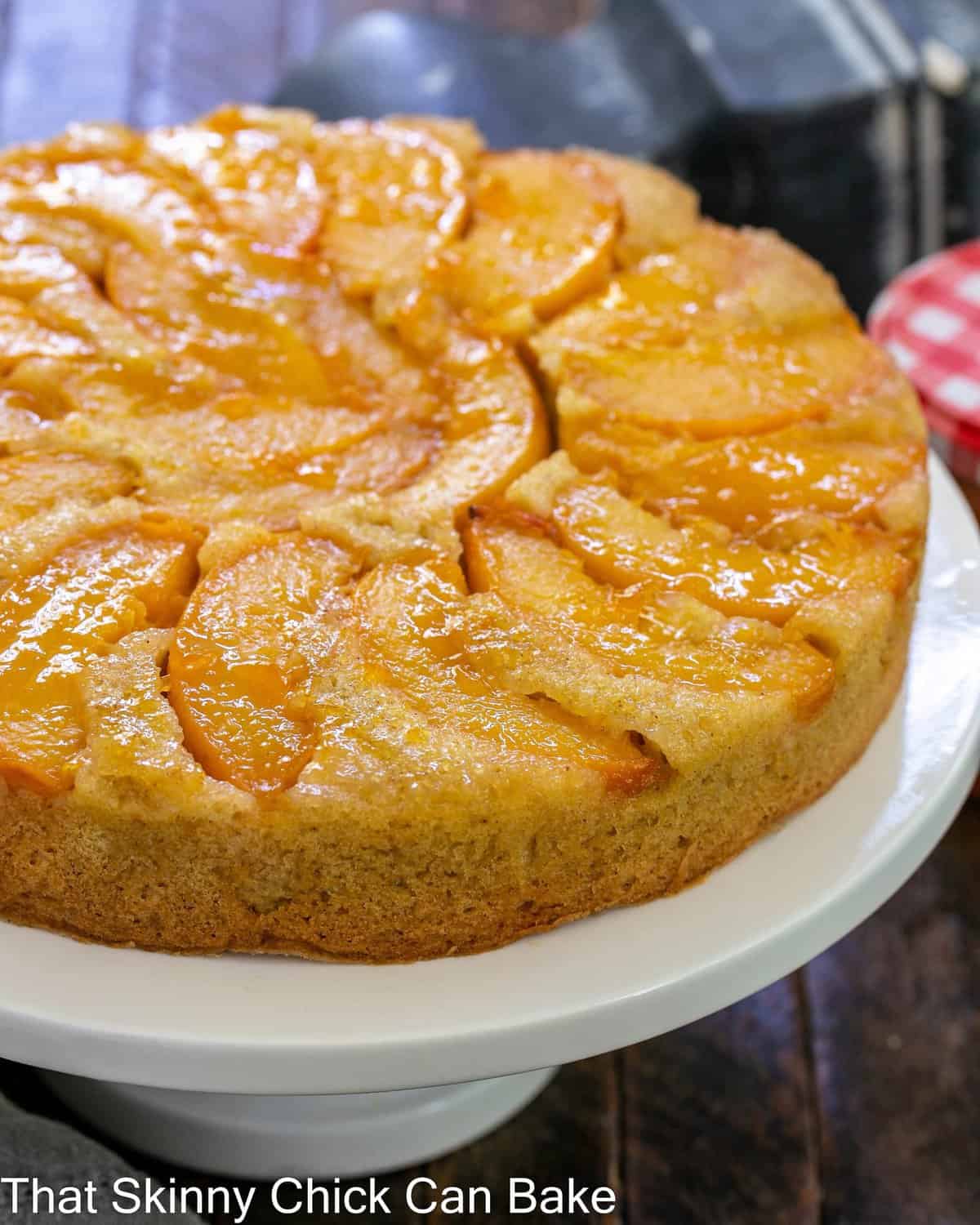 Peach upside down cake on a white ceramic cake stand.