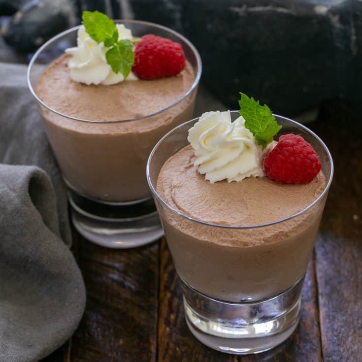 2 glass serving dishes of easy chocolate mousse with a raspberry, whipped cream and mint garnish