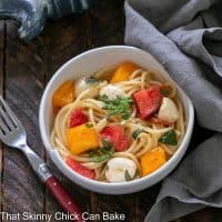 Overhead view of Caprese pasta in a white bowl with a red handled fork