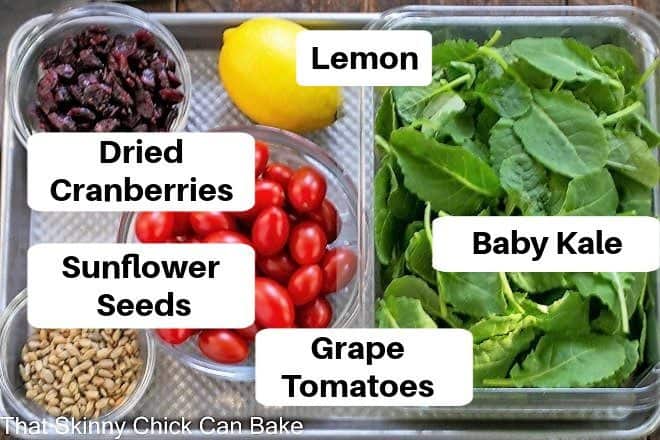 Overhead view of labeled kale salad ingredients on a sheetpan.