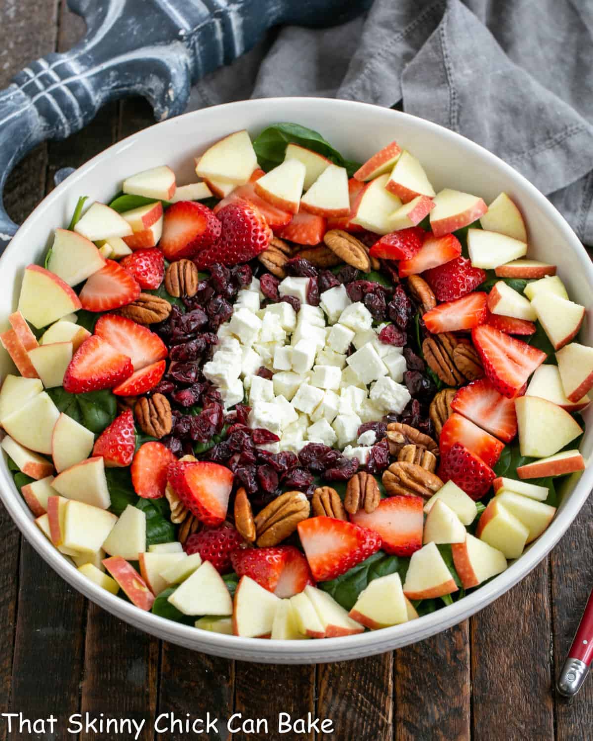 Overhead view of Spinach Salad with Strawberries and Feta in a white serving bowl.