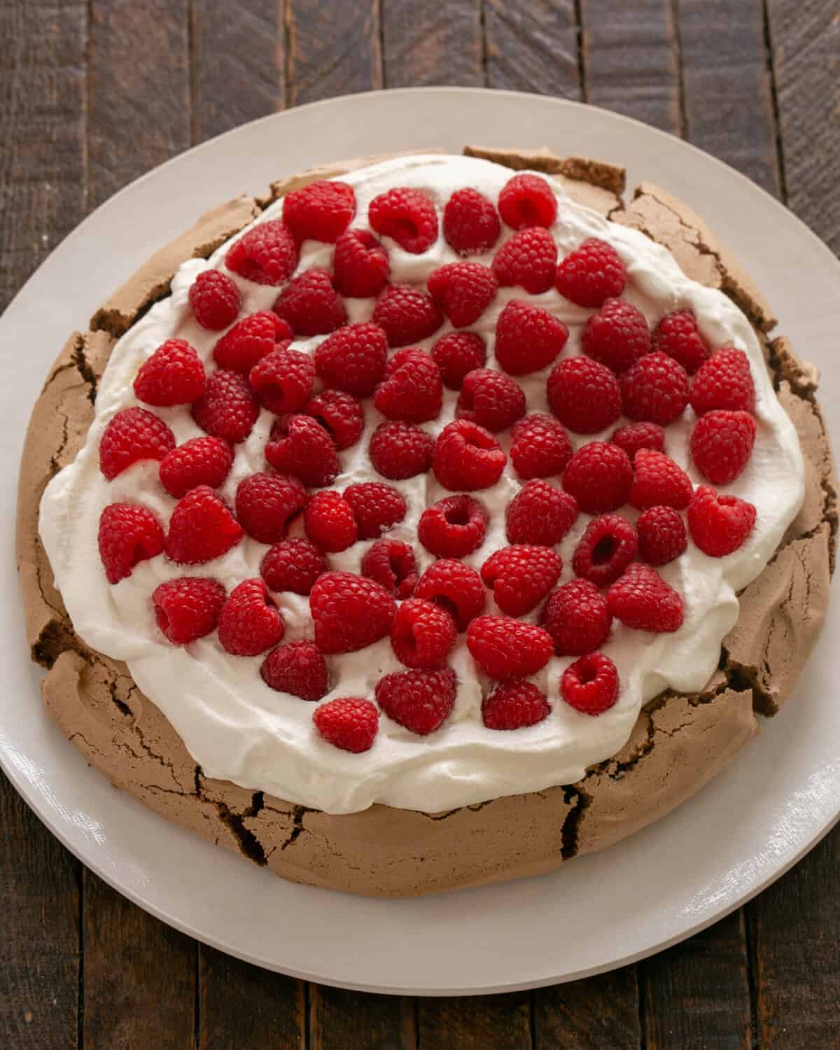 Pavlova cooled and topped with whipped cream and berries.