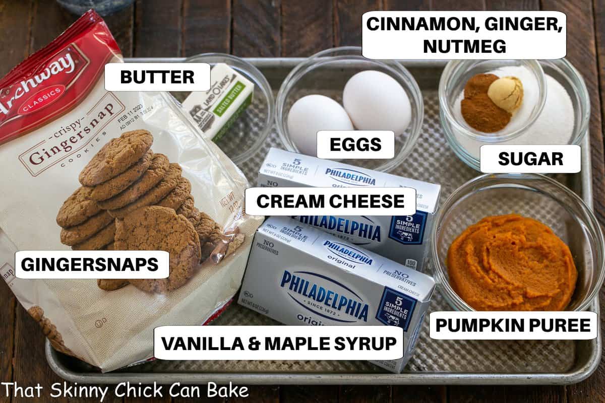 Labeled ingredients for pumpkin cheesecakes on a metal sheet pan.