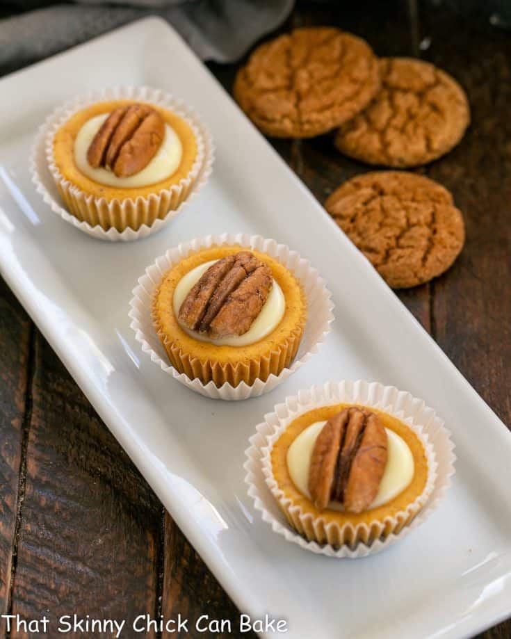 Mini pumpkin cheesecakes on a white ceramic tray.