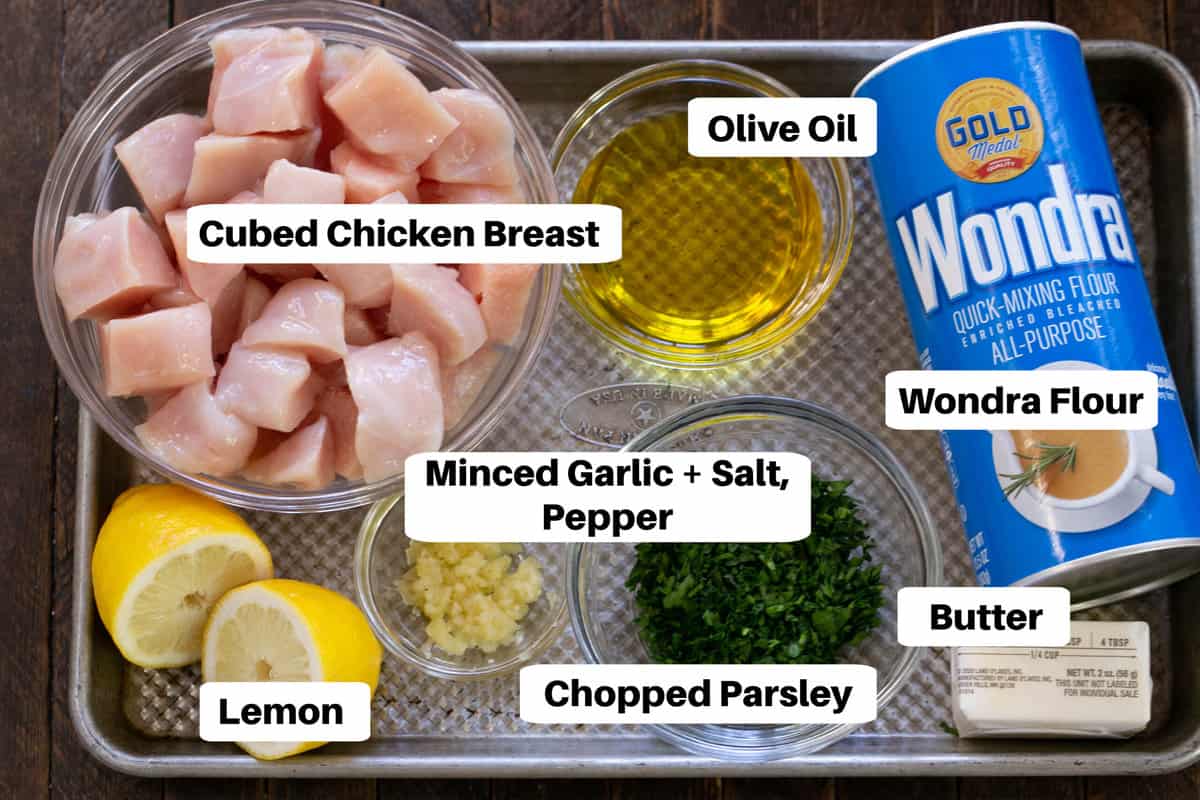 Chicken with parsley and garlic ingredients with labels on a sheet pan.