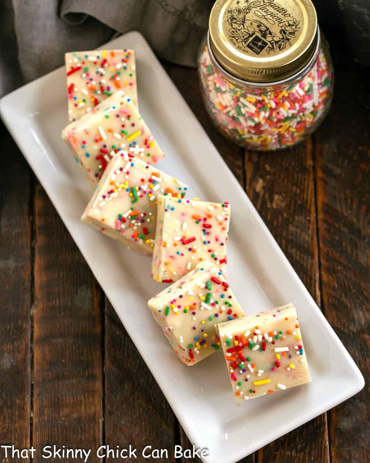 Squares of cake batter fudge on a white ceramic tray.