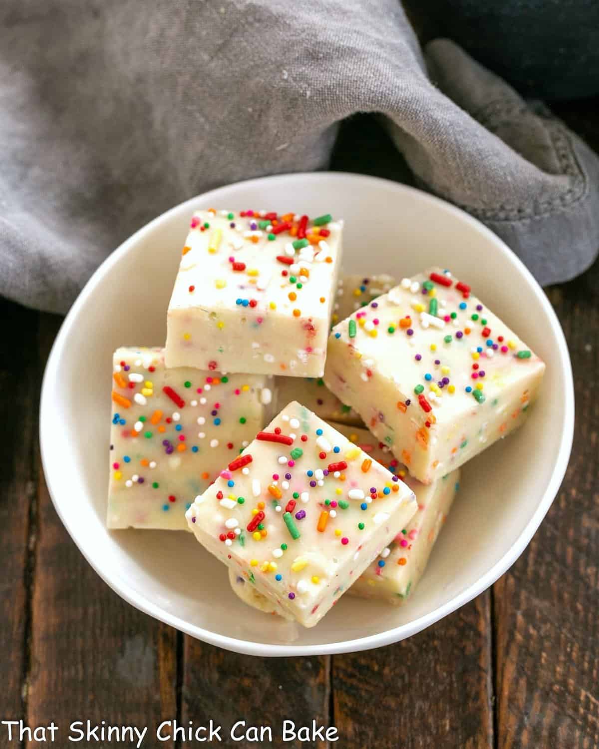 Squares of cake batter fudge in a white bowl.