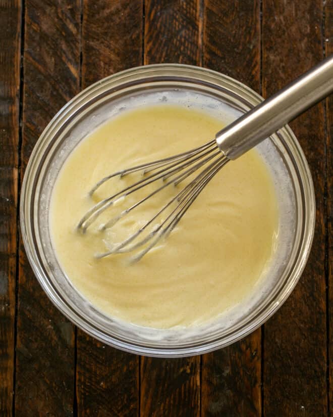 Broccoli salad dressing in a bowl with a whisk.