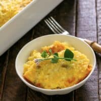 Fresh Corn Casserole in a small white bowl with an herb garnish.