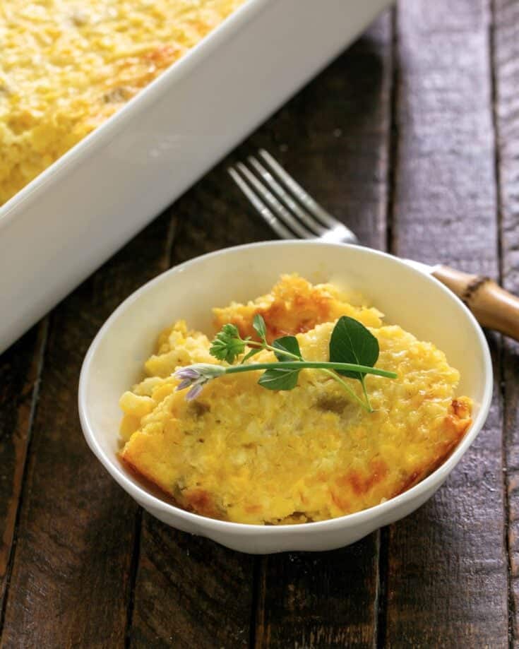 Fresh Corn Casserole in a small white bowl with an herb garnish.