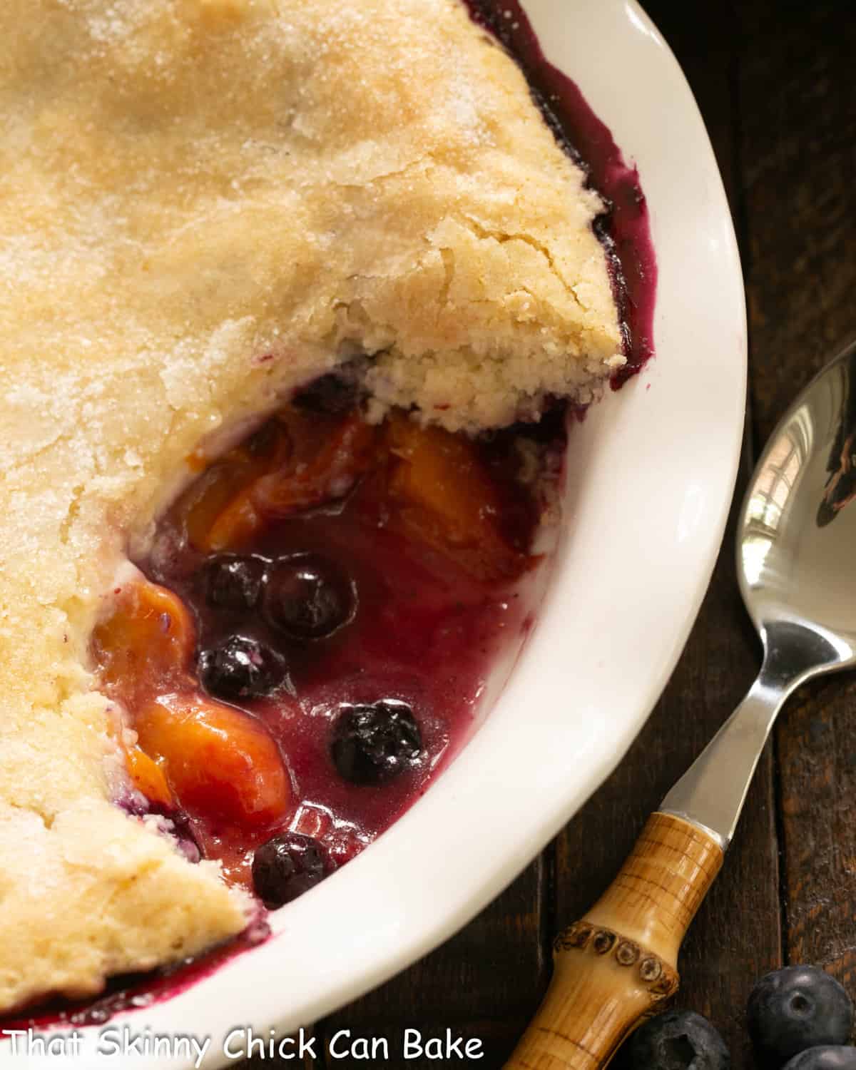 Close view of peach blueberry cobbler with a spoonful removed.