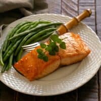 Marinated salmon for two on a white plate with a fork and green beans.