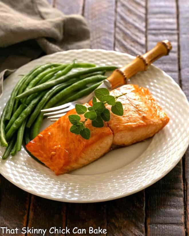 Marinated salmon for two on a white plate with a fork and green beans.