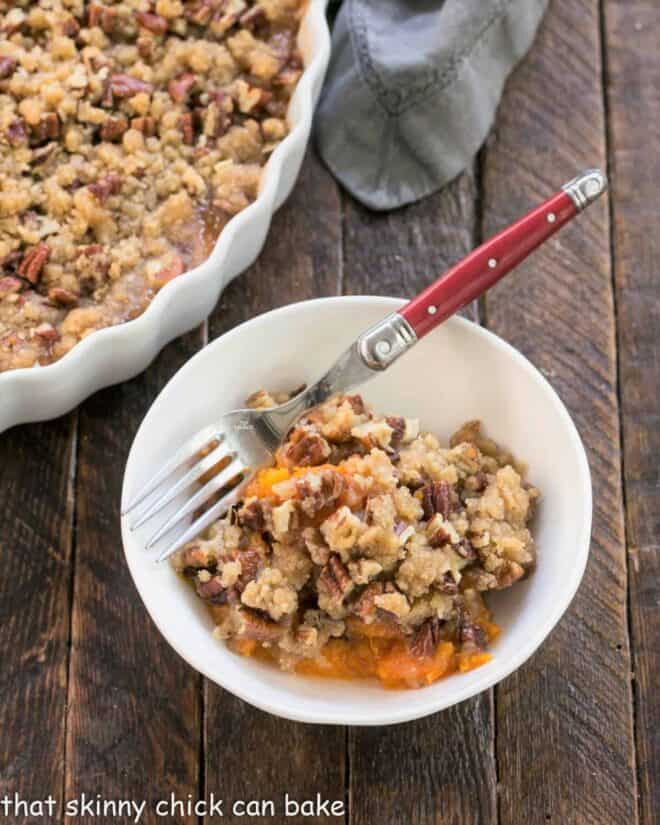 Serving of sweet potato casserole in a white bowl with a fork.
