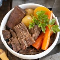 Pot roast and vegetables in a white ceramic bowl.