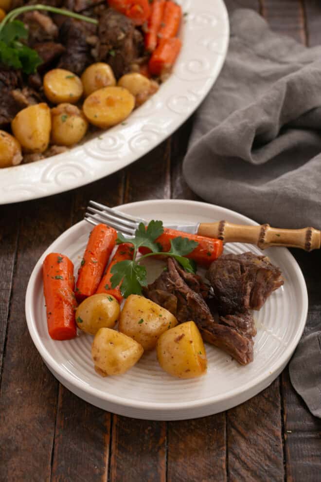 Pot roast serving next to platter.