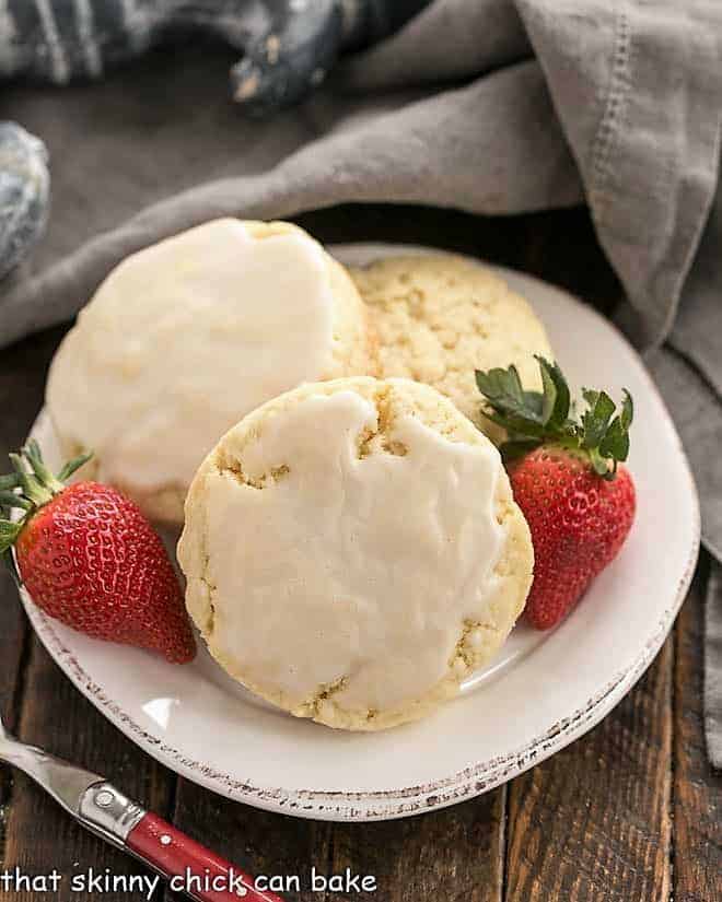 3 vanilla bean scones on a white plate with strawberries.