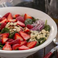 Strawberry, Spinach, Blue Cheese salad in a white serving bowl.