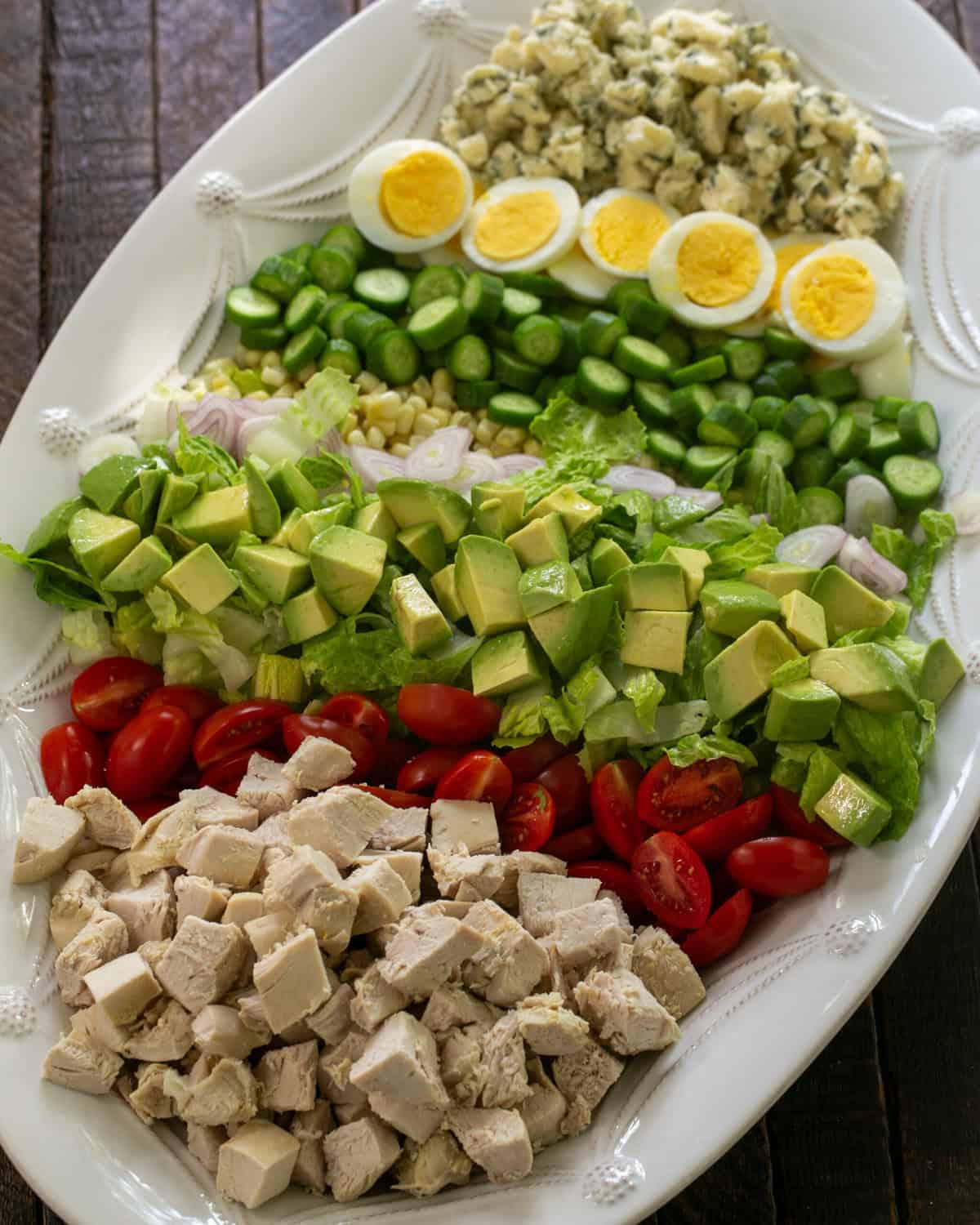 Overhead view of a composed Cobb salad on a white serving plate.