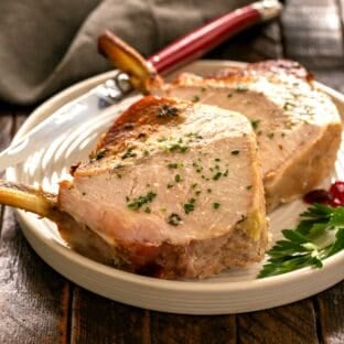 2 slices of a crown roast of pork on a round white plate.