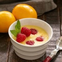 Meyer Lemon Mousse in a white ramekin garnished with fresh raspberries and mint.