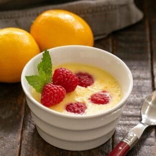 Meyer Lemon Mousse in a white ramekin garnished with fresh raspberries and mint.