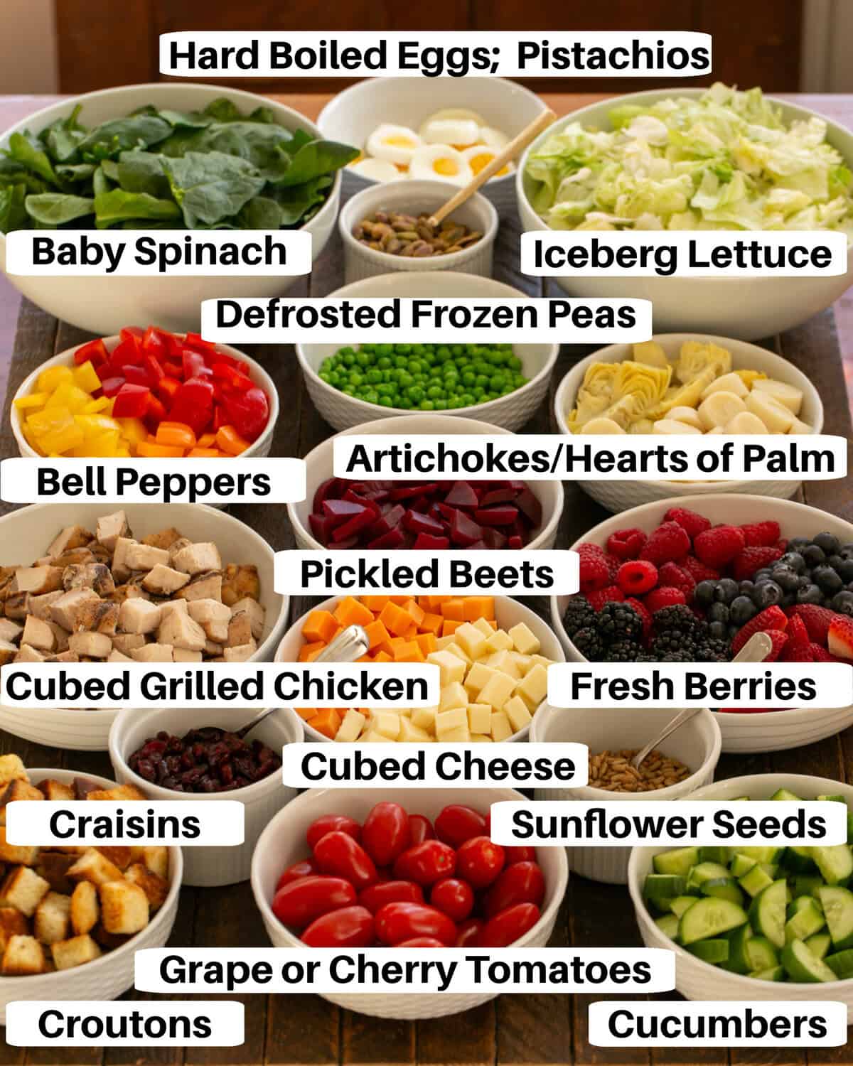 Salad bar ingredients in white bowls with labels.