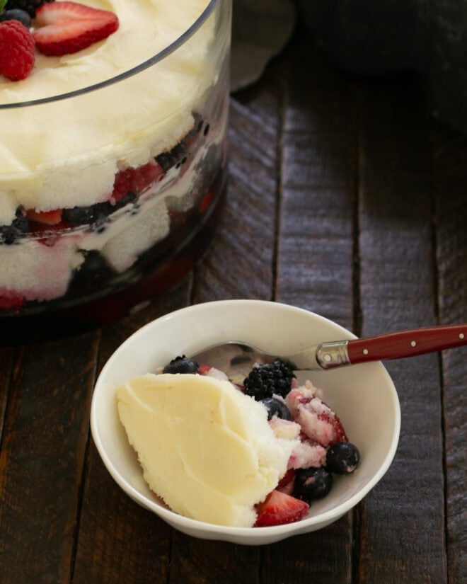Small bowl of berry trifle with a spoon off to the side of the serving bowl.