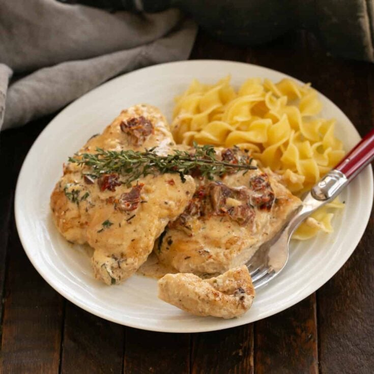 Marry Me Chicken on a white plate with pasta and a fork